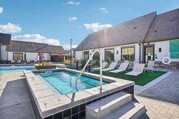 A swimming pool in front of a house with a pool and lounge chairs